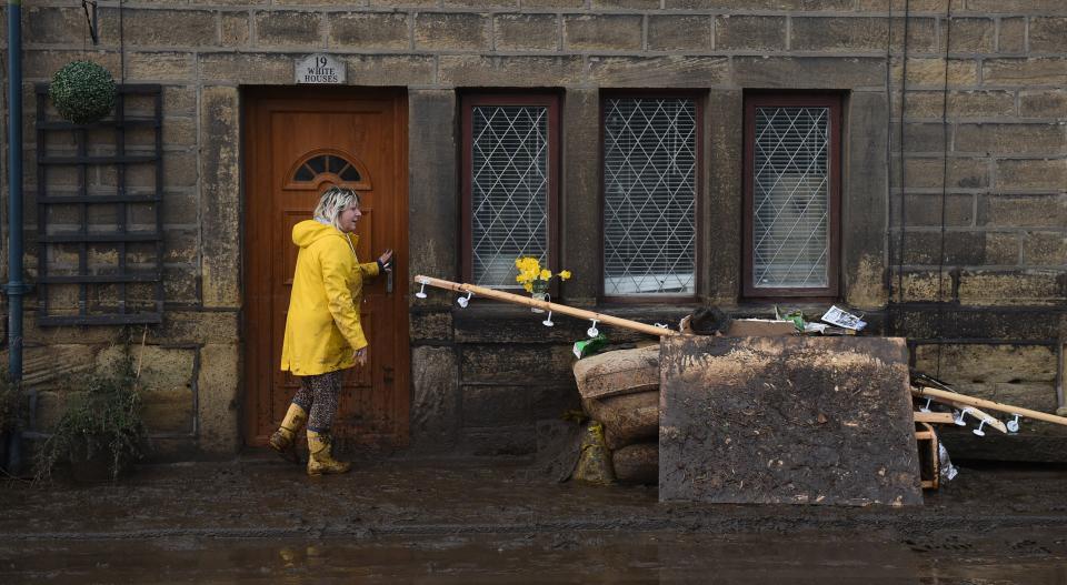 A woman clears debris outside a house in Mytholmroyd, northern England, on February 10, 2020 after flooding brought by Storm Ciara. - Storm Ciara grounded hundreds of flights Monday and left swatches of Europe without power after unleashing torrential rain and causing flash flooding that cancelled football matches in Britain. (Photo by Oli SCARFF / AFP) (Photo by OLI SCARFF/AFP via Getty Images)