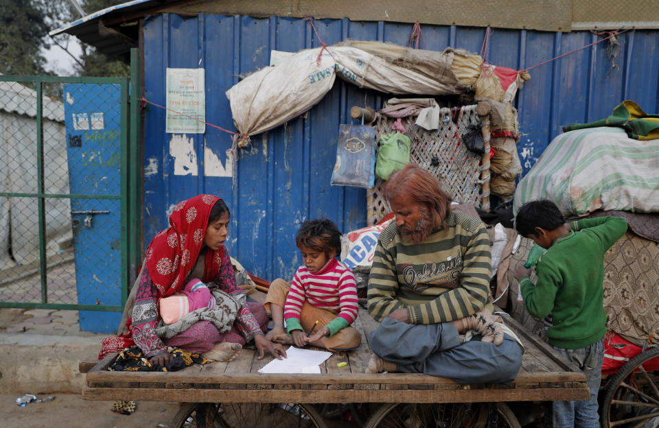 <p>A homeless woman helps her son Farmaan with his homework as they sit on a bicycle cart, their belongings hanging on a wall, in New Delhi, India, Wednesday, Jan. 16, 2019. Some 800 million people in the country live in poverty, many of them migrating to big cities in search of a livelihood and often ending up on the streets. (AP Photo/Altaf Qadri) </p>