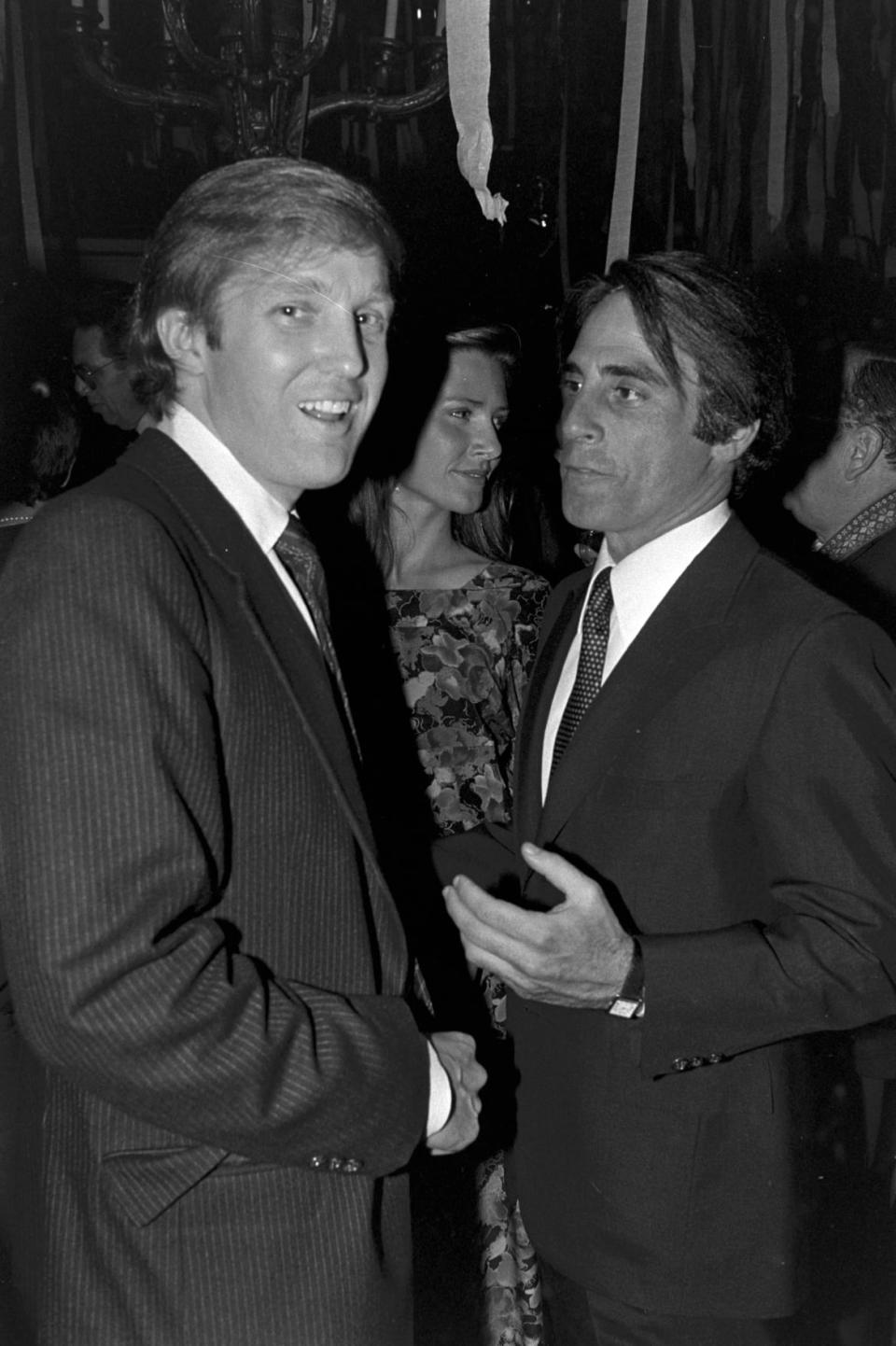 Donald Trump in his 30s in black and white staring at the camera with another man to his right