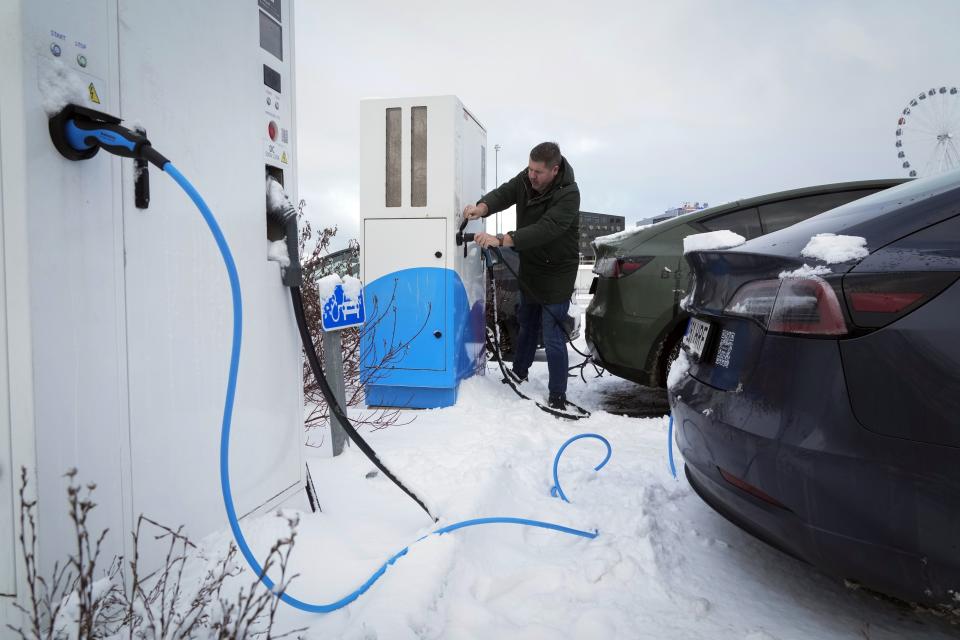 A driver charges an electric car at a parking lot of a shopping mall in Tallinn, Estonia, Saturday, Feb. 11, 2023. Many electric vehicle batteries lose power when it's very cold. (AP Photo/Sergei Grits)