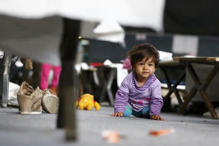 A migrant child looks on as it sits on the ground at an improvised temporary shelter in a sports hall in Hanau, Germany, September 24, 2015. REUTERS/Kai Pfaffenbach