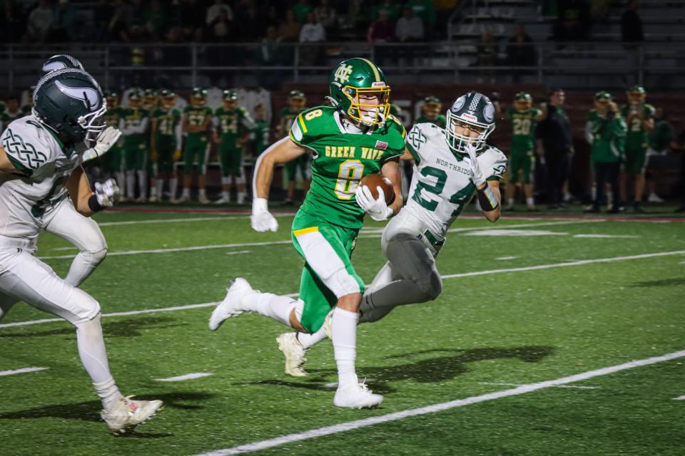 Newark Catholic senior Grant Moore breaks into the open field with Northridge senior Brody Booher (24) in pursuit at White Field on Friday, Oct. 21, 2022. The Green Wave beat the visiting Vikings 49-0.