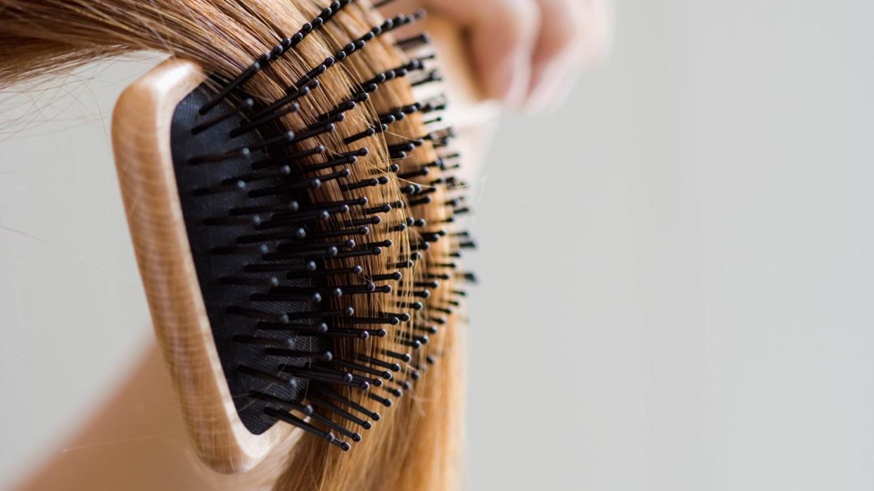 Close up image of woman brushing her blonde hair