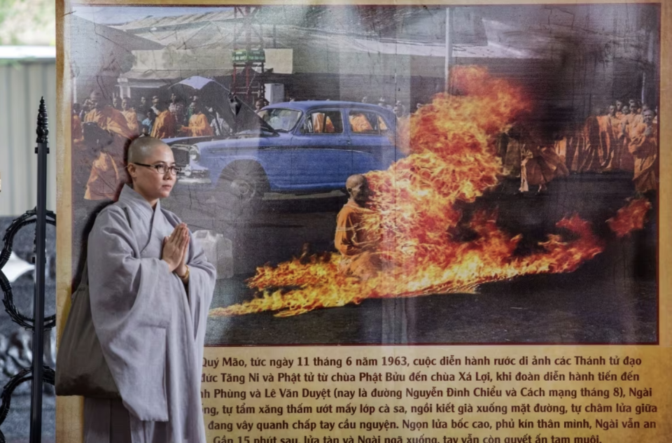 A Buddhist monk stands on June 3, 2018 in Ho Chi Minh City next to a banner with a picture of monk Thich Quang Duc, who set himself on fire on a busy Saigon street corner in 1963. (Kao Nguyen/AFP/Getty Images)