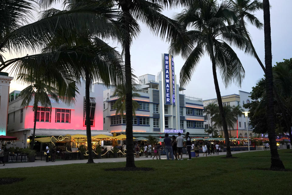 People walk along Ocean Drive, Friday, Sept. 24, 2021, in Miami Beach, Fla. For decades, this 10-block area has been one of the most glamorized spots in the world, made cool by TV shows like Miami Vice, where the sexiest models gathered at Gianni Versace's ocean front estate and rappers wrote lines about South Beach's iconic Ocean Drive. (AP Photo/Lynne Sladky)