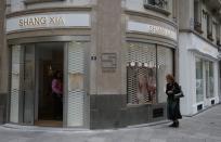 A woman walks past the shop of the young brand Shang Xia on its opening day in Paris September 11, 2013. Shang Xia, the Chinese-born brand backed by French luxury goods group Hermes, opened its first shop outside its home market in Paris on Wednesday to test appetite among non-Chinese customers for its handcrafted products. The brand is trying to build a business centred on the revival of traditional Chinese crafts such as porcelain, cashmere felt and furniture, that were all but nearly destroyed by China's proletarian Cultural Revolution. REUTERS/Jacky Naegelen (FRANCE - Tags: FASHION BUSINESS)