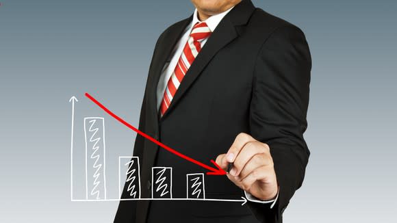 Man in a business suit drawing a downward-sloping chart in the air