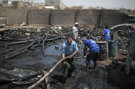 Workers use a water hose to put down a fire at a vehicle oil store hit by Saudi-led airstrikes in Sanaa, Yemen, Thursday, July 2, 2020. (AP Photo/Hani Mohammed)