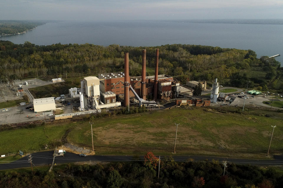 A brief patch of early morning sunlight brightens the landscape around the Greenridge Generation power plant on the banks of Seneca Lake, Friday, Oct. 15, 2021, in Dresden, N.Y. One Bitcoin mining operation in central New York came up with a novel solution in finding cheap energy to run the power-gobbling computer arrays that create and transact cryptocurrency: It took over Greenidge Generation which now produces about 44 megawatts to run 15,300 computer servers, plus additional electricity it sends into the state's power grid. (AP Photo/Julie Jacobson)