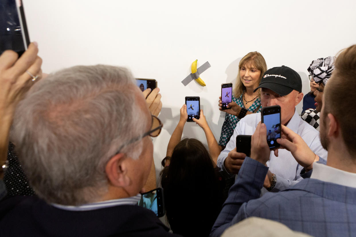 A woman poses for a photo next to a banana attached with duct-tape that replaces the artwork 'Comedian' by the artist Maurizio Cattelan, which was eaten by David Datuna, in Miami Beach, Florida, December 7, 2019.  REUTERS/Eva Marie Uzcategui     TPX IMAGES OF THE DAY