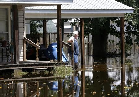 A man wades through flood waters in Sorrento, Louisiana, U.S., August 20, 2016. REUTERS/Jonathan Bachman