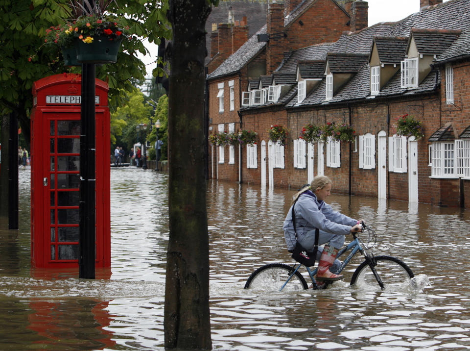 A girl cycles through flood waters in Stratford Upon-Avon, central England, July 21, 2007. Torrential rain caused flash floods and brought transport chaos, the Highways Agency said on Saturday. As many as 2,000 people had to be taken to emergency centres in the Cotswolds, one of England's most picturesque regions.    REUTERS/Darren Staples  (BRITAIN)