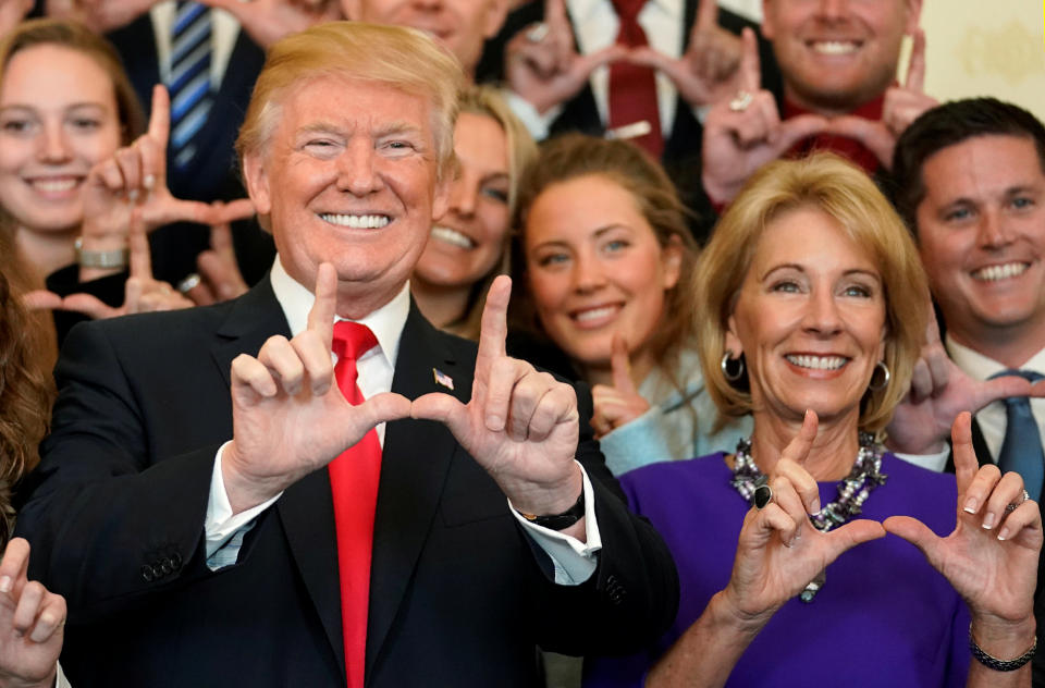 U.S. President Donald Trump and Education Secretary Betsy DeVos make "U" symbols with their hands while posing with the Utah Skiing team as they greet members of Championship NCAA teams at the White House in Washington, U.S., November 17, 2017.   REUTERS/Joshua Roberts