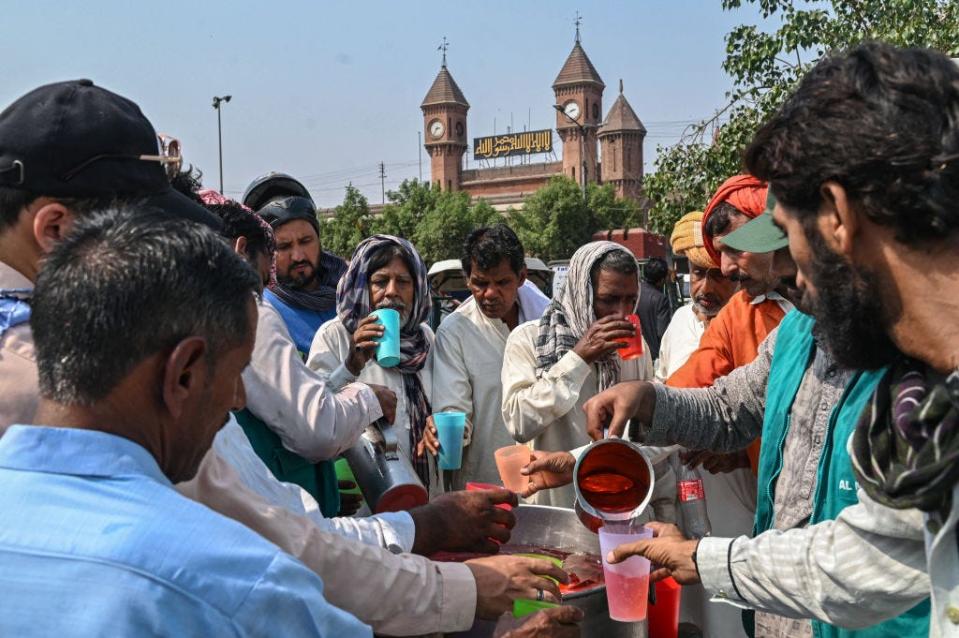 Volunteers hand out cold drinks to citizens at a 'heatwave relief camp' along the road during a hot summer day in Lahore on May 31, 2024.