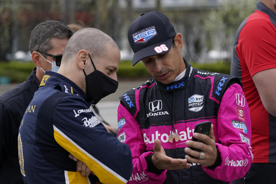 Tony Kanaan, of Brazil, left foreground, talks with Helio Castroneves, of Brazil, before testing at the Indianapolis Motor Speedway, Thursday, April 8, 2021, in Indianapolis. (AP Photo/Darron Cummings)