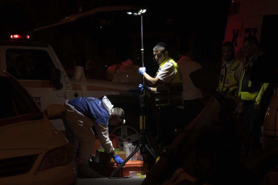 An Israeli police officer, left, investigates the scene of a stabbing attack in the town of Elad, Israel, Thursday, May 5, 2022. Israeli medics say at least three people were killed in a stabbing attack near Tel Aviv on Thursday night. Israeli police said they suspect it was a militant attack. (AP Photo/Maya Alleruzzo)