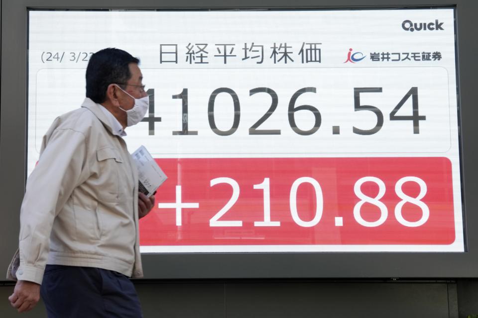 A person walks in front of an electronic stock board showing Japan's Nikkei 225 index at a securities firm Friday, March 22, 2024, in Tokyo. Stocks were mostly lower Friday in Asia after Wall Street tapped fresh records, led by big gains in chipmakers. (AP Photo/Eugene Hoshiko)