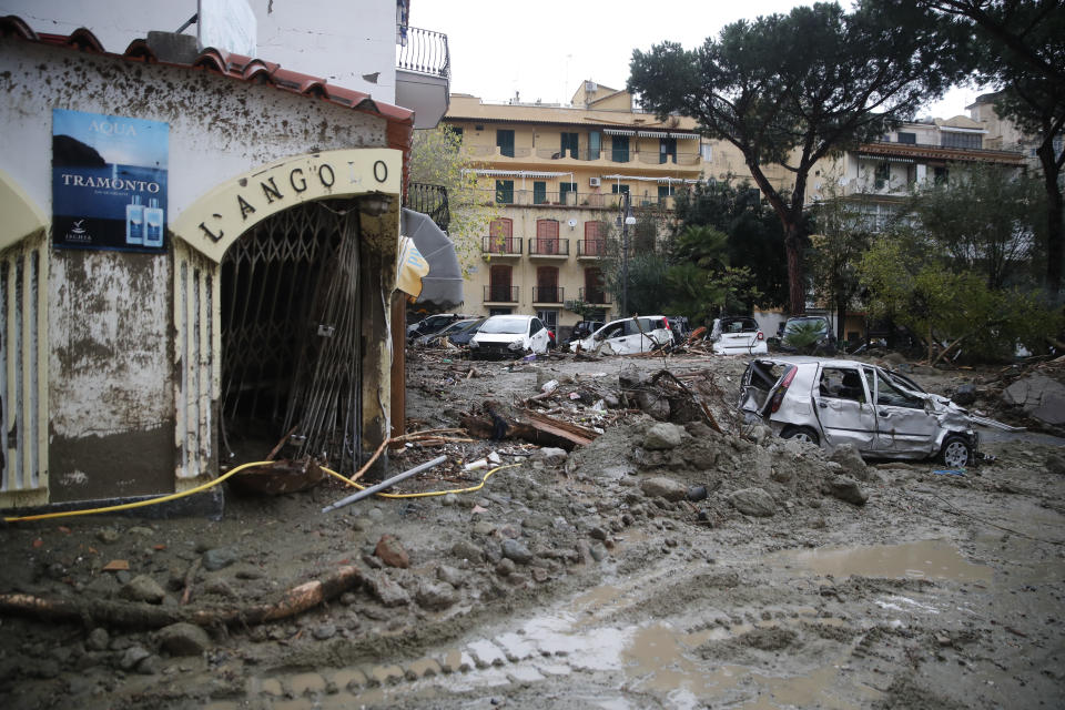 Cars stand in the mud after heavy rainfall triggered landslides that collapsed buildings and left as many as 12 people missing, in Casamicciola, on the southern Italian island of Ischia, Saturday, Nov. 26, 2022. Firefighters are working on rescue efforts as reinforcements are being sent from nearby Naples, but are encountering difficulties in reaching the island either by motorboat or helicopter due to the weather. (AP Photo/Salvatore Laporta)