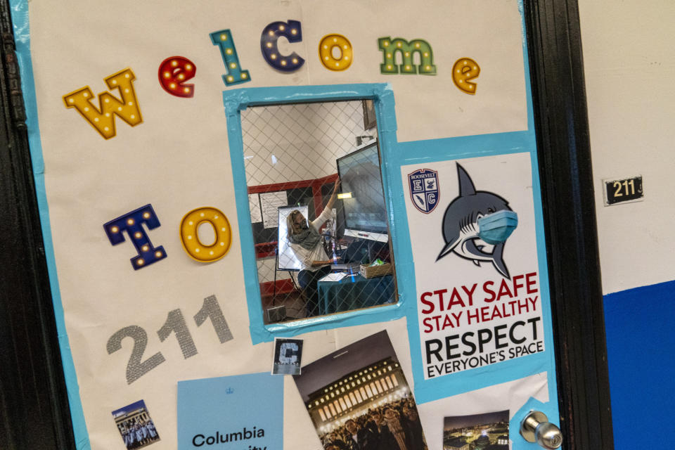 Framed through a classroom window, a teacher conducts a class during the coronavirus outbreak at Roosevelt High School - Early College Studies, Thursday, Oct. 15, 2020, in Yonkers, N.Y. (AP Photo/Mary Altaffer)