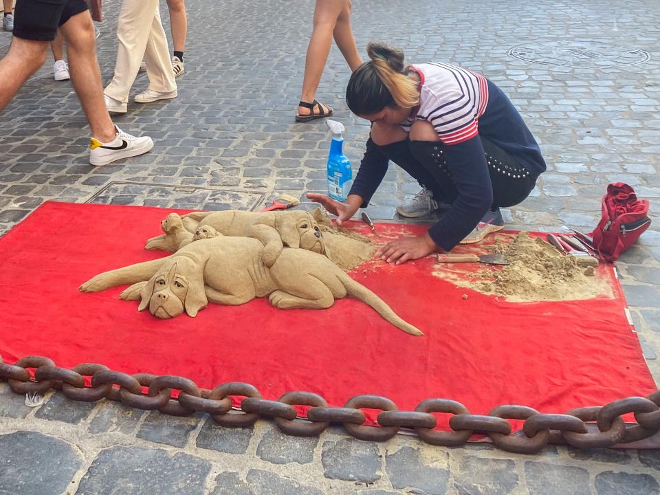 A artist sculpts dogs from sand on the streets of Rome.