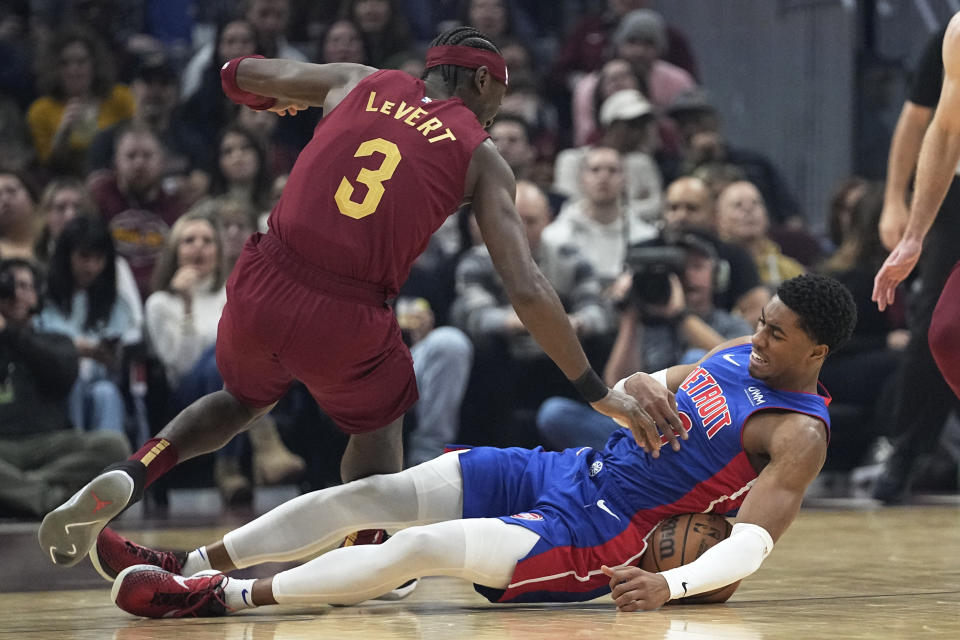 Cleveland Cavaliers guard Caris LeVert (3) reaches for the ball held by Detroit Pistons guard Jaden Ivey, right, in the first half of an NBA basketball game, Wednesday, Jan. 31, 2024, in Cleveland. (AP Photo/Sue Ogrocki)
