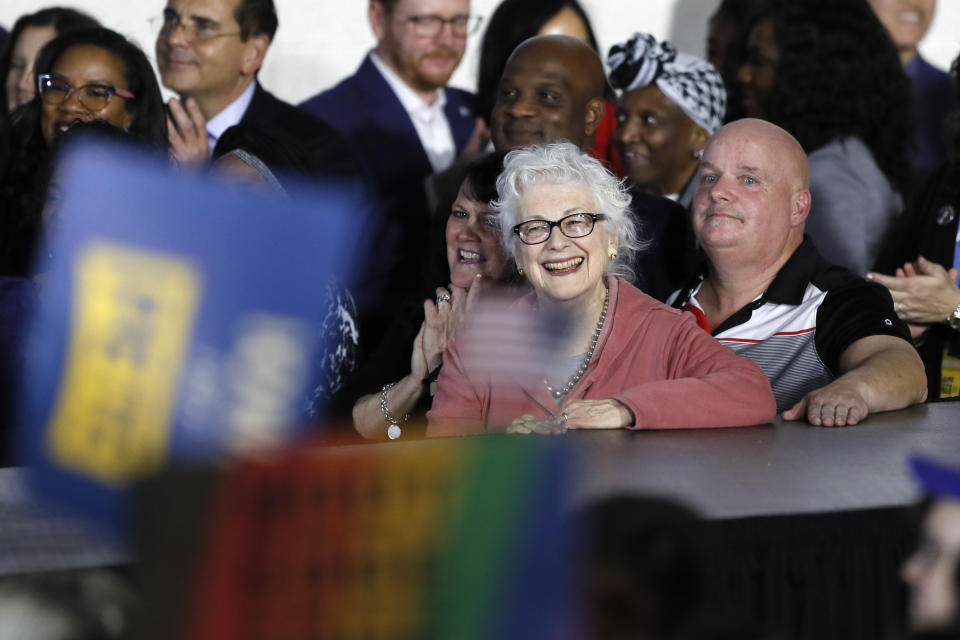 Anne Montgomery smiles as she listens to her son Democratic presidential candidate former South Bend, Ind., Mayor Pete Buttigieg speak to supporters at a caucus night campaign rally, Monday, Feb. 3, 2020, in Des Moines, Iowa. (AP Photo/Charlie Neibergall)