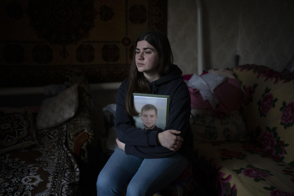 Anna Korostenska hugs a picture of her late fiancee, Oleksii Zavadskyi, while posing for a portrait at his grandmother's house in Bucha, Ukraine, Thursday, Feb. 2, 2023. As the conflict that killed her loved one still rages on, Anna wrestles with a question that all of war-torn Ukraine must grapple with: After loss, what comes next? (AP Photo/Daniel Cole)