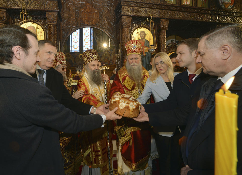 Bosnian Serb political leader Milorad Dodik, second left, holds a cake marking St. Stevan's day, the patron-saint of Republic of Srpska, and the 30th anniversary with Serbian Orthodox Church Patriarch Porfirije, fourth left, Prime Minister of Republika Srpska Zeljka Cvijanovic, third right, and Banja Luka mayor Drasko Stanivukovic, second right, in Banja Luka, northern Bosnia, Sunday, Jan. 9, 2022. Dodik was slapped with new U.S. sanctions for alleged corruption. Dodik maintains the West is punishing him for championing the rights of ethnic Serbs in Bosnia — a dysfunctional country of 3.3 million that's never truly recovered from a fratricidal war in the 1990s that became a byname for ethnic cleansing and genocide. (AP Photo/Radivoje Pavicic)