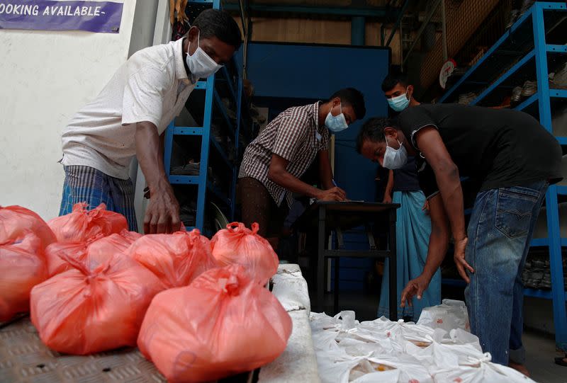 Migrant workers living in a factory-converted dormitories collect the food delivered by non-governmental organization Alliance of Guest Workers Outreach (AGWO) during the coronavirus disease (COVID-19) outbreak in Singapore