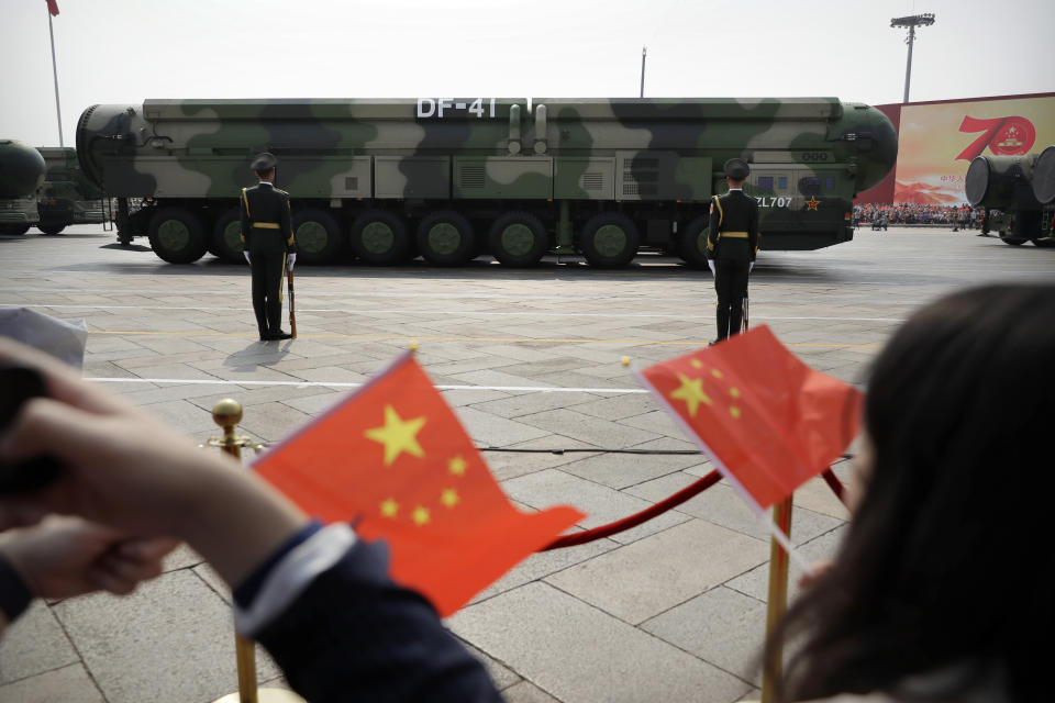 FILE - Spectators wave Chinese flags as military vehicles carrying DF-41 nuclear ballistic missiles roll during a parade to commemorate the 70th anniversary of the founding of Communist China in Beijing on Oct. 1, 2019. (AP Photo/Mark Schiefelbein, File)