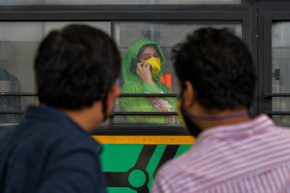 A woman (centre) speaks on her phone on a bus at the Bengaluru International Airport (AFP via Getty Images)