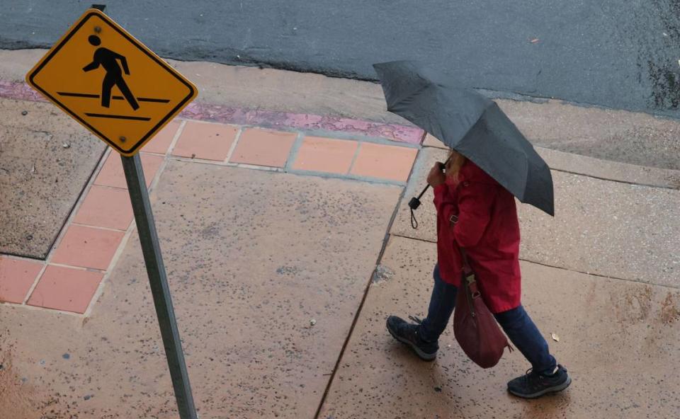 A pedestrian walks in the rain Monday morning, Dec. 18, 2023, on Pacific Street in San Luis Obispo.