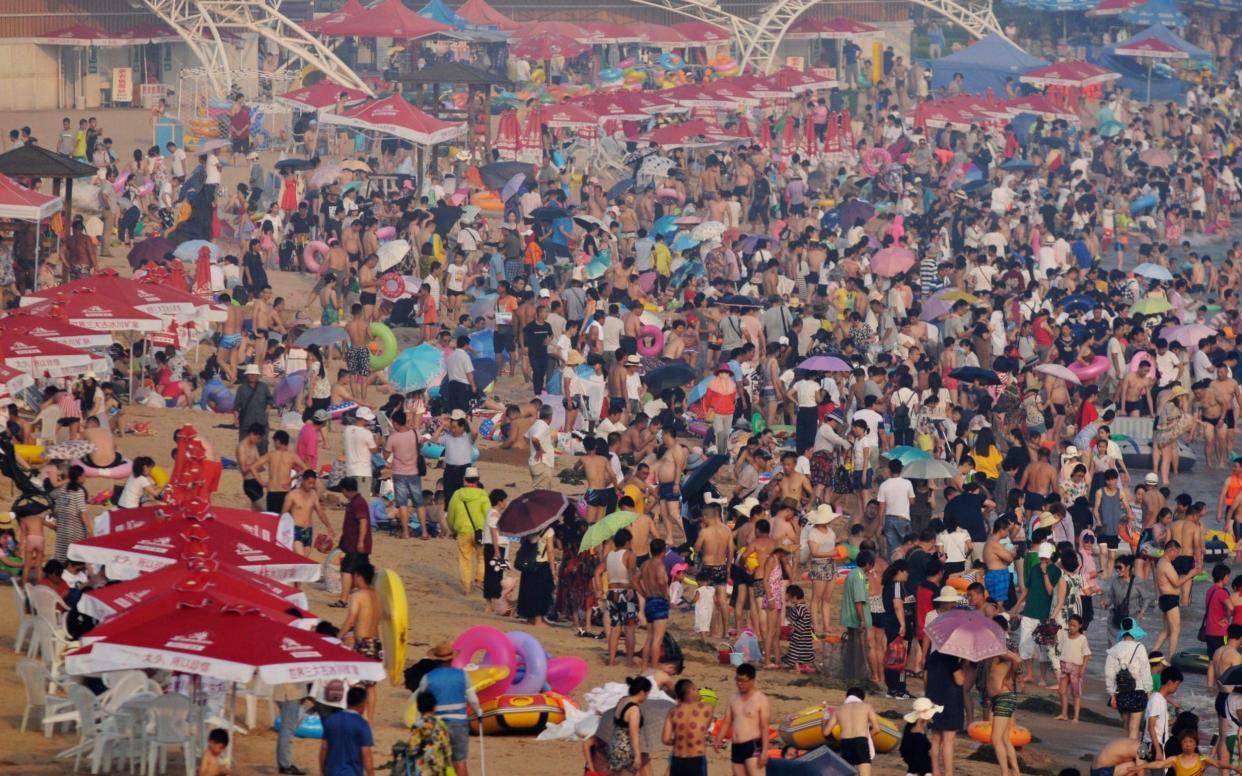 Visitors flock to a beach in eastern China's Shandong Province. With the world's population set to peak at 9.7 billion, a new study says China will succeed US as the top global economic power before America resumes the top spot.  - CHINATOPIX