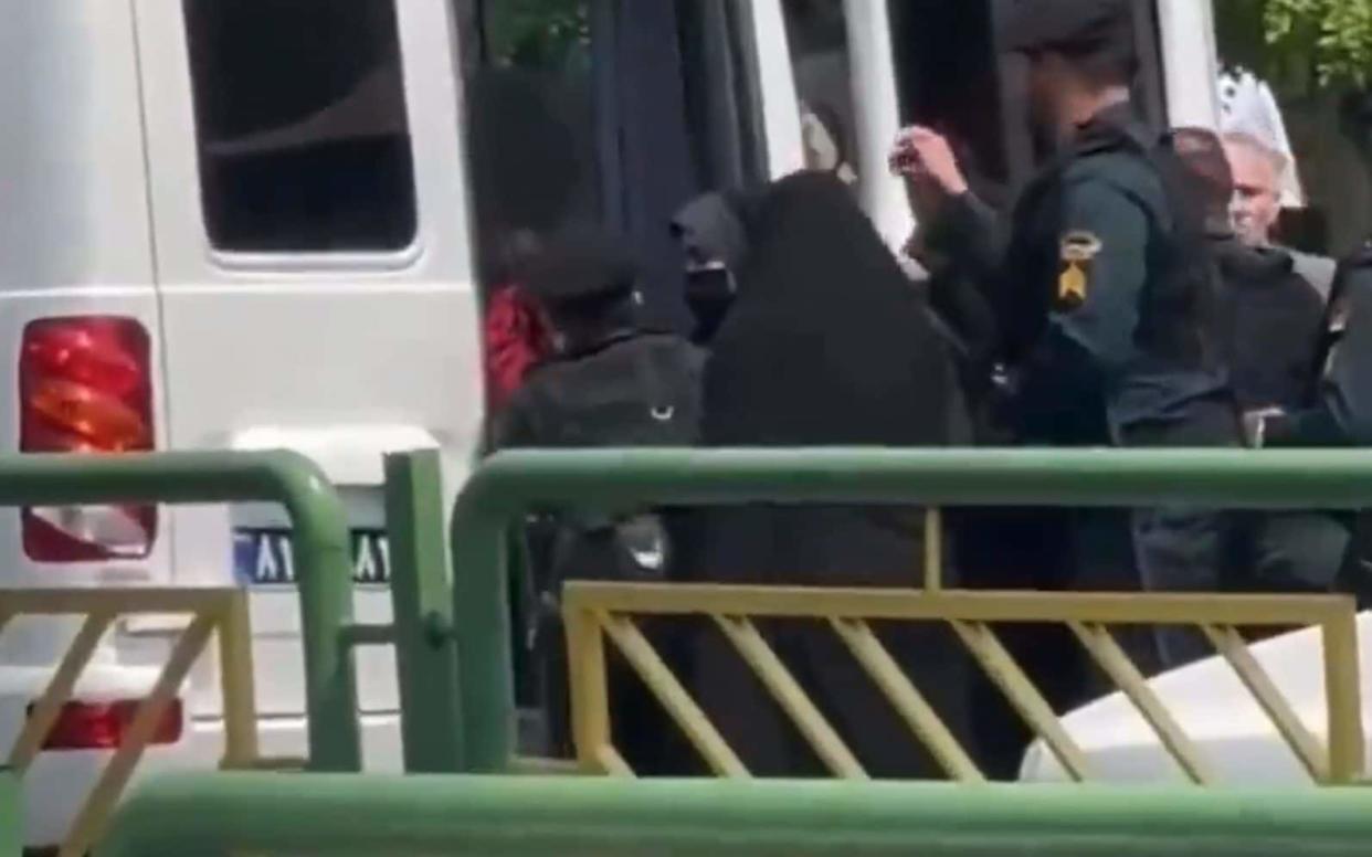 A women being bundled into one of the white vans used by the morality police to round up those deemed to be violating the country's strict dress codes