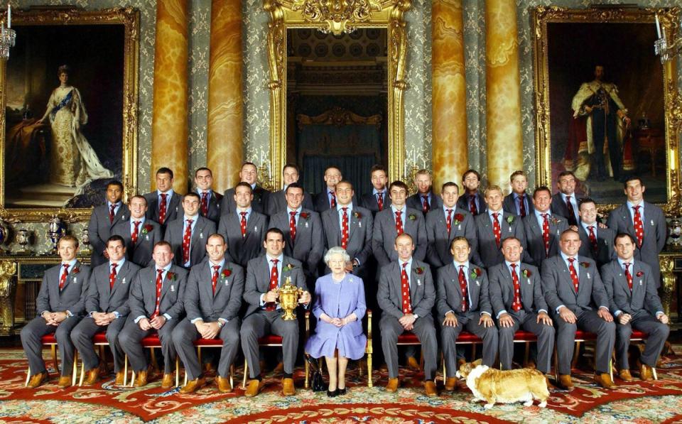 Queen Elizabeth II poses, with the England rugby squad at a reception at Buckingham Palace in London to celebrate winning the Rugby World Cup, accompanied by one of her beloved Corgis. (POOL/AFP via Getty Images)
