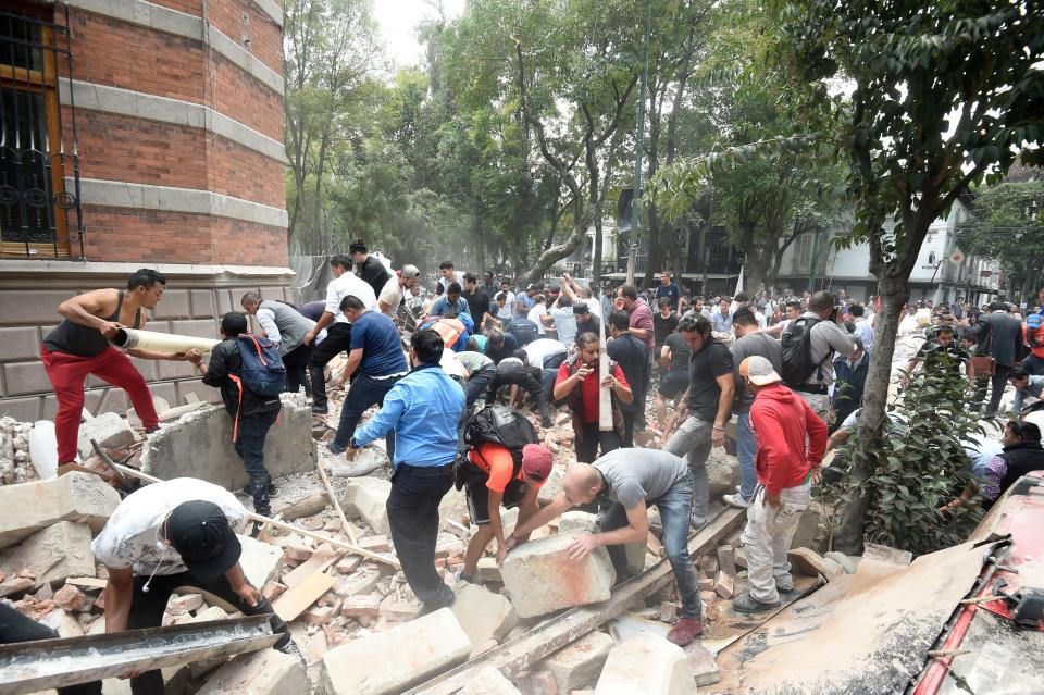 People remove debris of a damaged building.