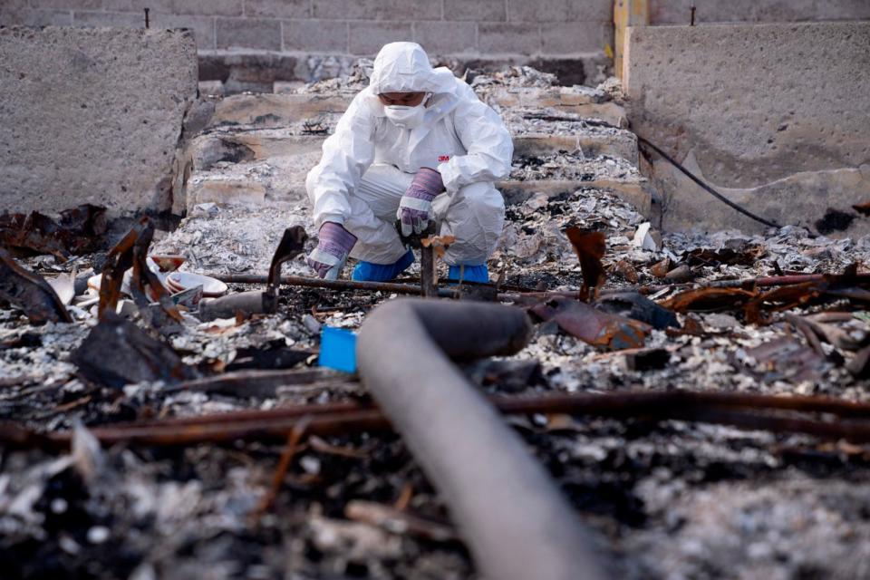 PHOTO: Rev. Ai Hironaka, resident minister of the Lahaina Hongwanji Mission, squats down to look at debris where the altar once stood in the grounds of his temple destroyed by wildfire, Dec. 7, 2023, in Lahaina, Hawaii. (Lindsey Wasson/AP)