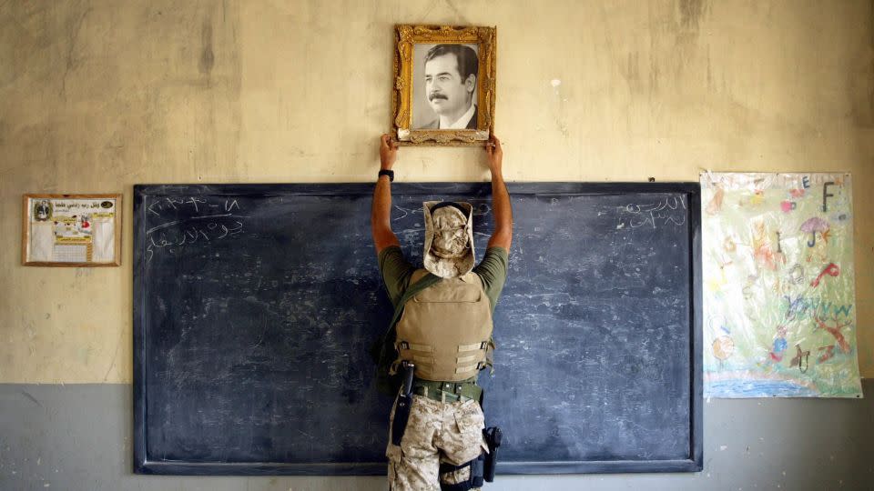 A US Marine pulls down a picture of Saddam Hussein at a school in Al-Kut, Iraq, 2003. - Chris Hondros/Getty Images