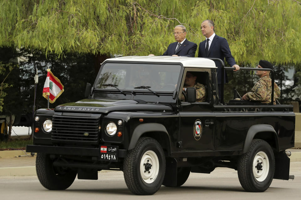 Lebanese President Michel Aoun, left, and Defense Minister Elias Bou Saab, right, stand on a military vehicle before they review Lebanese soldier units during a military parade to mark the 76th anniversary of Lebanon's independence from France at the Lebanese Defense Ministry, in Yarzeh near Beirut, Lebanon, Friday, Nov. 22, 2019. Lebanon's top politicians attended Friday a military parade on the country's 76th Independence Day, appearing for the first time since the government resigned amid nationwide protests now in their second month. (AP Photo/Hassan Ammar)