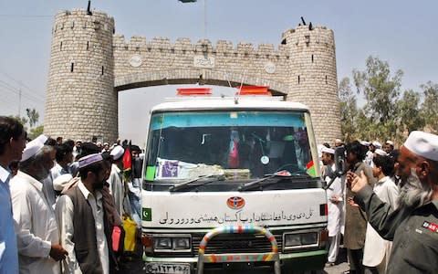 Pakistani officials welcome a bus coming from Jalalabad as it arrives at the Khyber Pass - Credit: TARIQ MAHMOOD/AFP/Getty Images