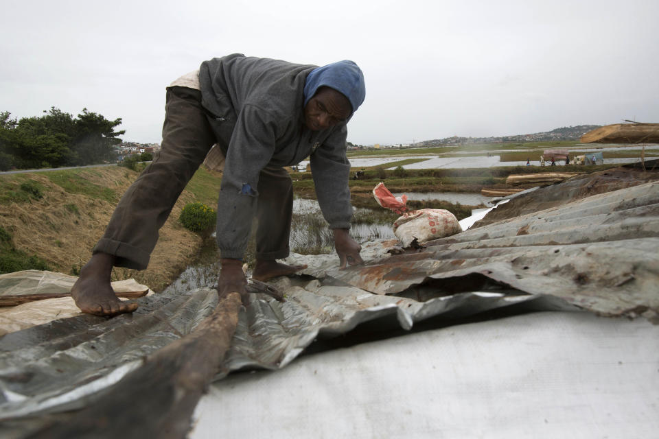 A man secures his home during adverse weather, in Antananarivo, Madagascar, Saturday, Feb. 5, 2022. Weather officials forecast that the full force of Cyclone Batsirai is to hit Madagascar Saturday evening. Madagascar's meteorology department said the cyclone is gaining strength as it blows across the Indian Ocean, with gale-force winds reaching peaks of 235 kilometers (145 miles) per hour. (AP Photo/Alexander Joe)