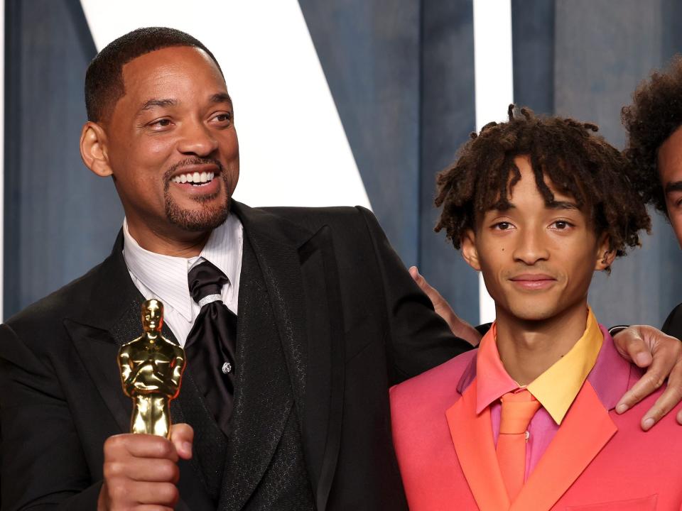 Will smiling with a buzzcut and facial hair and Jaden smiling with short dreadlocks.