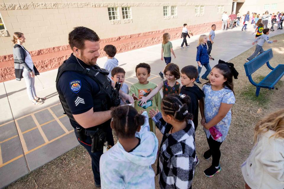 SRO Sgt. Fred Cuthbertson hands out stickers to second graders during recess at Sunset Hills Elementary School on Nov. 30, 2023.