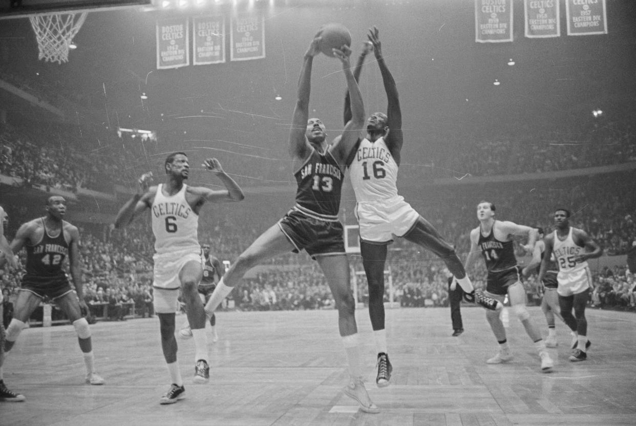 (Original Caption) Boston: Wilt Chamberlain (13) of the Warriors' fights for rebound with (16) Tom Sanders of the Celtics' as Bill Russell (6,L) looks on. Action took place in the first period of the fifth game for the NBA championship at Boston Garden here.