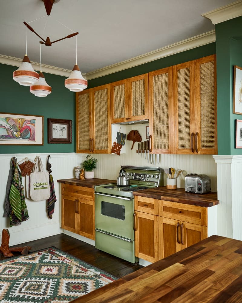 Green vintage inspired stove in green kitchen with caned wooden cabinets.