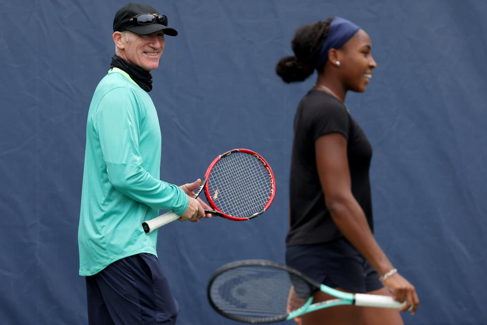 Brad Gilbert standing on a tennis court with Coco Gauff