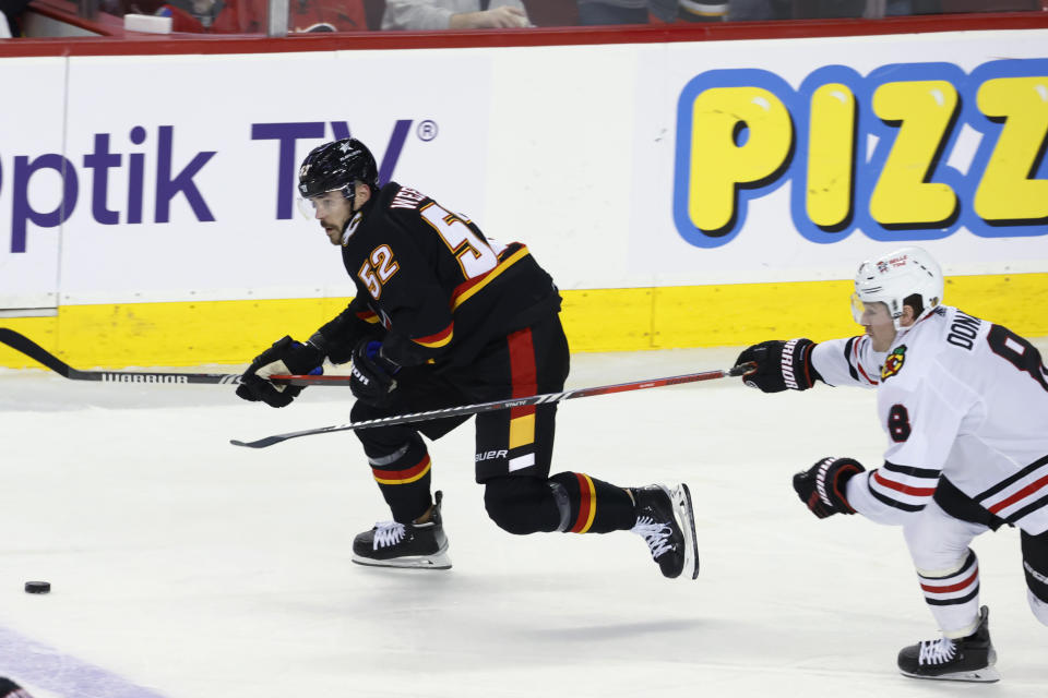 Chicago Blackhawks' Ryan Donato, right, races for the puck against Calgary Flames' MacKenzie Weegar during the first period of an NHL hockey game Saturday, Jan. 27, 2024, in Calgary, Alberta. (Larry MacDougal/The Canadian Press via AP)