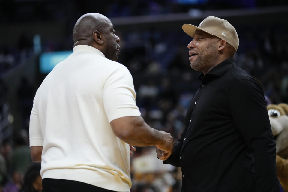 Magic Johnson greets Los Angeles Lakers coach Marvin Ham during the first half of a WNBA basketball game between the Phoenix Mercury and the Los Angeles Sparks in Los Angeles, Friday, May 19, 2023. (AP Photo/Ashley Landis)