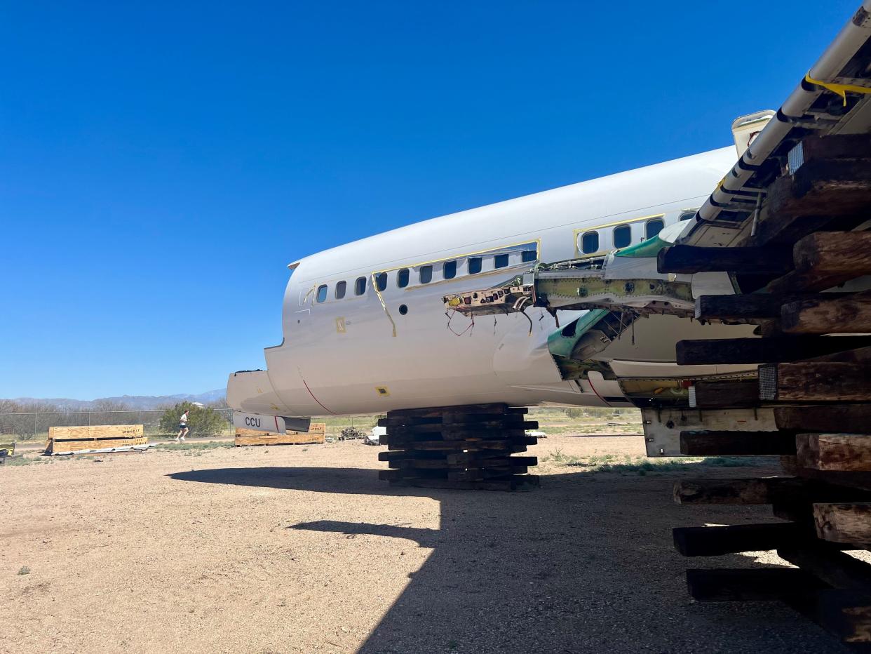 A white plane without a nose in an aircraft graveyard.
