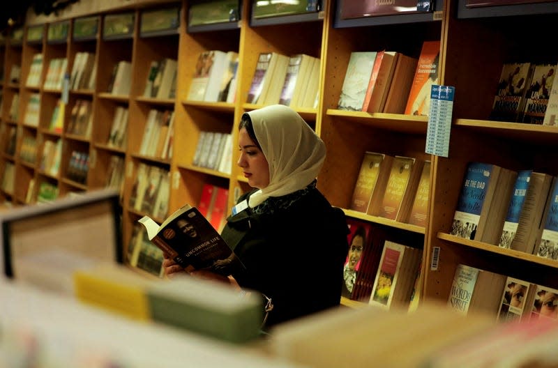 A woman in a headscarf reading in a bookshop